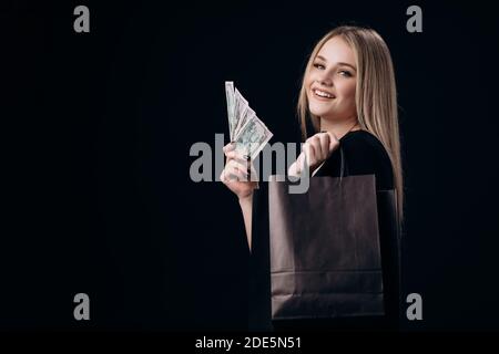 Blonde holding dollar banknotes and shopping bags Stock Photo