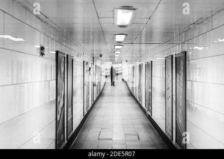 Quiet, empty London Underground Tube Station in Coronavirus Covid-19 pandemic lockdown, with one lone person on public transport when trains were reduced during travel ban Stock Photo