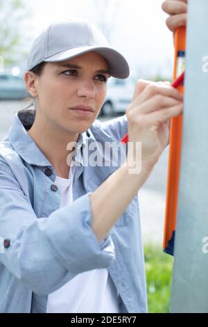 female contractor using spirit level on vertical post Stock Photo