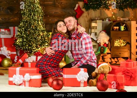 Christmas composition. evening before xmas. Enjoying spending time together in New Year Eve. Couple in love sitting next to Christmas tree. hugging among present boxes. romantic couple is having fun. Stock Photo