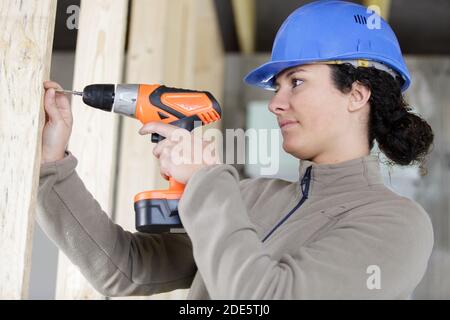 side view of female builder using cordless drill Stock Photo