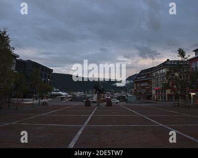 Square in the old center of Tromsø at shopping street Storgata with the arctic hunter monument (fangstmonument) in the evening on a cloudy day. Stock Photo