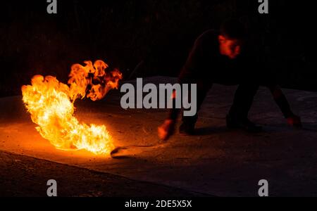 Fascinating and dangerous. Man manipulate with burning poi in dark. Burning fuel and energy. Sparks and lights. Night show. Fire performance. Flirt with danger. Stock Photo