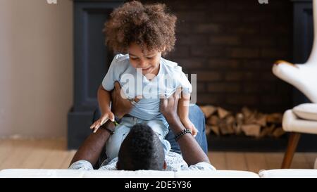 Happy black father and little son tickling giggling on bed Stock Photo