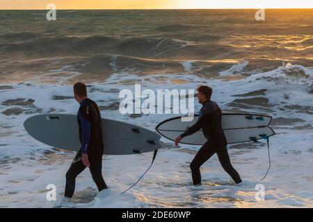 England, East Sussex, Eastbourne, Birling Gap, The Seven Sisters Cliffs and Beach, Two Male Surfers Walking on Beach Carrying Surfboards Stock Photo