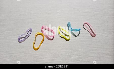Set of small multicolored elastic bands for hair on a white table. Stock Photo