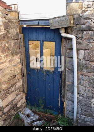 a close up view of a old damaged blue door leading into a old barn Stock Photo