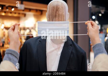 Medical mask is put on a mannequin with clothes, man in store. Help with the coronavirus pandemic Stock Photo