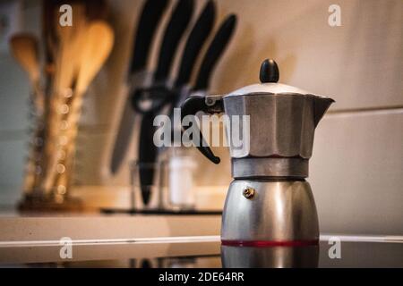 Making coffee from boiling water on hot stove with kitchen counter in background Stock Photo