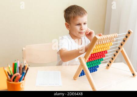 child solving maths exercises. 7 years old boy doing maths lessons sitting at desk in his room. Stock Photo