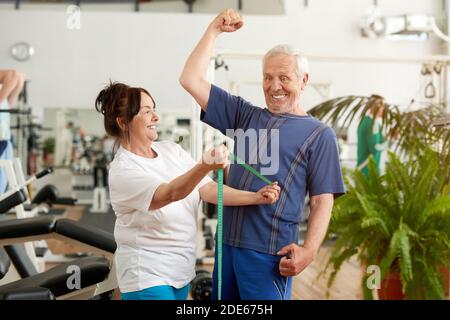 Funny senior man flexing his muscles at gym. Stock Photo