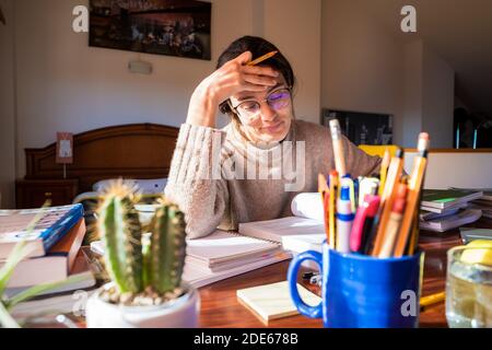 Young female student stressed on her desk in the bedroom, studying at home. Home concept. Stock Photo