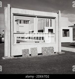 1960s, historical picture showing a large pre-cast concrete external wall panel with window frames on display in the grounds of the company, with small pre cast concrete slabs showing what they are orginally made from.  These wall panels were manufactured and suppiied in this era to builders of so called 'modern' housing, office and tower block construction projects. As the large concrete panels were made off-site, they reduced the cost and time of the build and were hard-wearing and fire safe.  With their stark external appearance, they were referre to as s 'Brutalist' style of architecture. Stock Photo