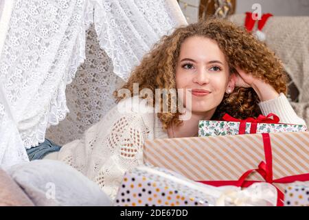 Pretty lady woman laying on Christmas giftboxes wear white knitted pullover Stock Photo