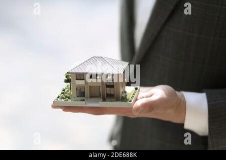 Businessman holding model house. Architecture, building, construction, real estate and property concept Stock Photo