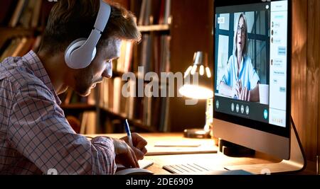 Male student wearing headphones video conference calling watching webinar. Stock Photo