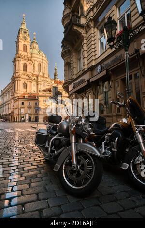 Harley Davidson motorbikes parked in side street in front of St Nicholas Church, Prague, Czech Republic Stock Photo