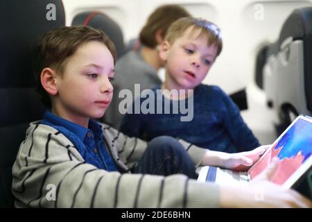 Brothers using tablet in plane at night Stock Photo