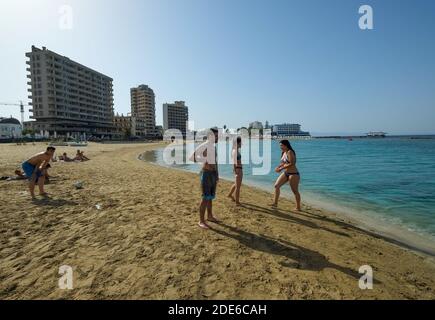 Varosha, Cyprus. Tourists play on the beach in front of abandoned hotels at Varosha, Famagusta, now part of Turkish occupied Northern Cyprus, (TRNC). Stock Photo