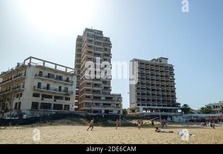 Varosha, Cyprus. Tourists play on the beach in front of abandoned hotels at Varosha, Famagusta, now part of Turkish occupied Northern Cyprus, (TRNC). Stock Photo