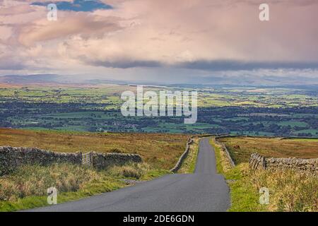 View looking down a Country Road near Staimore with the Eden Valley in the distance, Cumbria, England, UK.