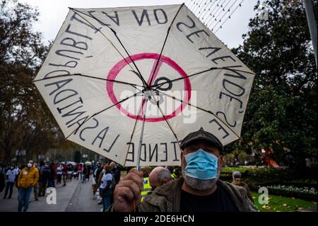 Madrid, Spain. 29th Nov, 2020. A man carrying an umbrella against budget cuts in healthcare during a demonstration in support of the public healthcare system and against the mistreatment of the sector during the coronavirus (COVID-19) pandemic. Credit: Marcos del Mazo/Alamy Live News Stock Photo