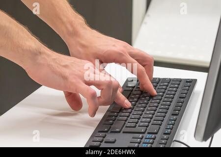 male hands typing on a black keyboard. Stock Photo