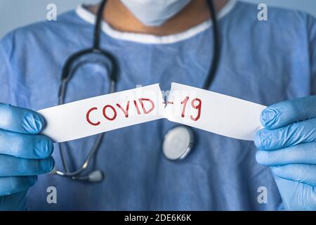 Doctor tears off the white paper that says Covid-19. Coronavirus outbreak concept. Stock Photo