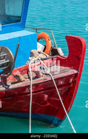 The colourful painted bows of a traditional Greek or Mediterranean fishing boat on a bright sunny day with ropes and nets. Stock Photo
