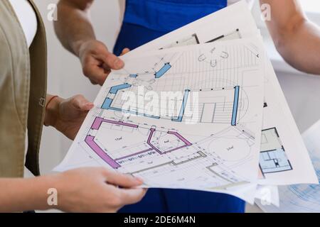 The woman holds the layout of the house and shows it to the builders. Close-up Stock Photo