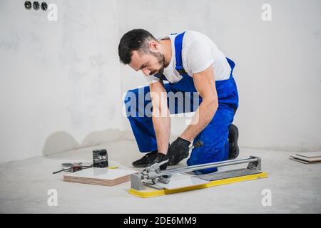 Young workman cuts tiles with a special tool Stock Photo