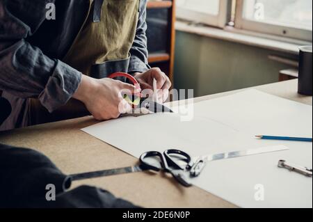 In a family shoe shop a young apprentice works with paper to create a pattern for shoes. Stock Photo