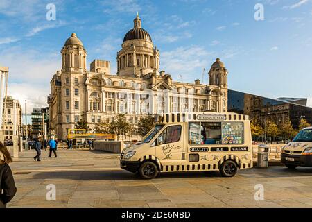 An ice cream van branded "Liverpool City Ices" is parked in front of the Port of Liverpool Building at the Pier Head in Liverpool, England; the curved façade of the Museum of Liverpool is visible in the background on the right. Stock Photo