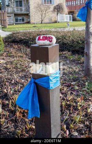 On the light pole (tied with a blue ribbon) there is a small rock with the word LOVE written on it. Stock Photo