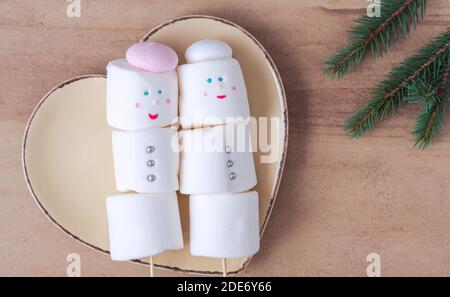Cute marshmallow snowmen on the heart shaped plate Stock Photo