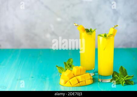 Refreshing summer cocktails made of mango, cold drink or a drink with ice on a blue gray background. Fresh summer ice cold mango cocktail or juice wit Stock Photo