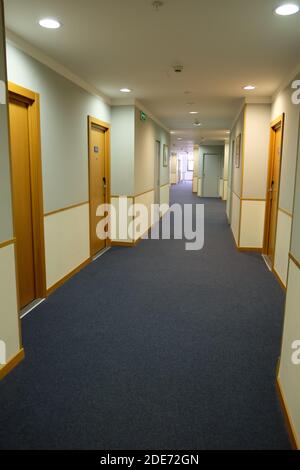 A view of a long corridor in the hotel, lit by daylight. Vacation concept, travel, quarantine, lockdown, hotel business losses, empty hotels. Vertical Stock Photo