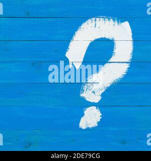 A question mark drawn with a white paint brush on a blue wooden plank wall. ?oncept of unsolved problems, indecision and riddle. Stock Photo
