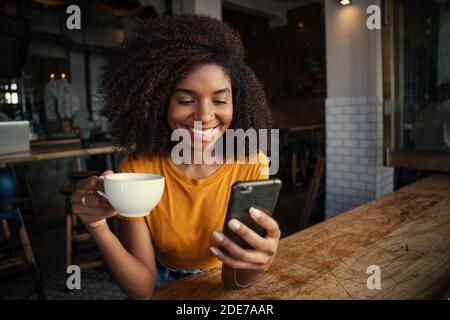 African female taking selfie with delicious coffee in trendy cafe  Stock Photo