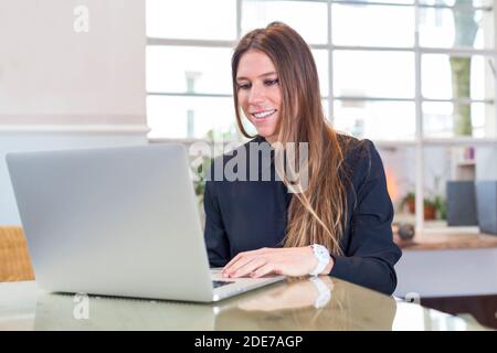 Deutschland, München, Portrait junge Geschäftsfrau im Büro mit Laptop Stock Photo
