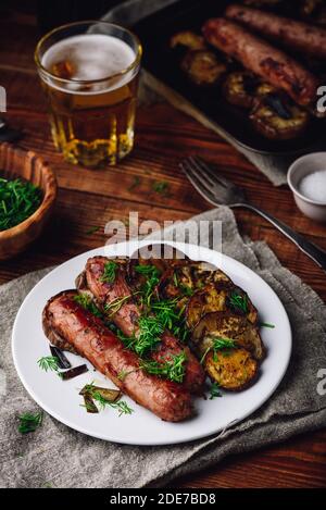 Pork Sausages Baked with Eggplant Slices on White Plate Garnished with Fresh Dill Stock Photo