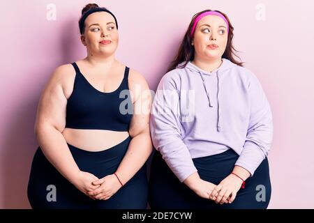 Young plus size twins wearing sportswear smiling looking to the side and staring away thinking. Stock Photo