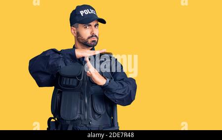 Young hispanic man wearing police uniform doing time out gesture with hands, frustrated and serious face Stock Photo