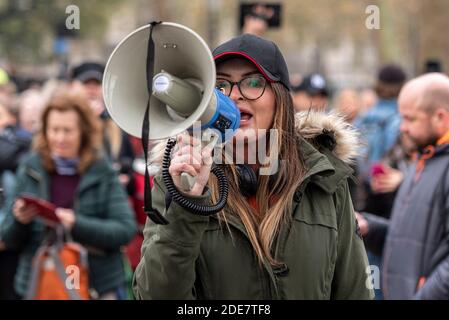 White Caucasian female shouting through a megaphone at a COVID 19 Coronavirus anti lockdown protest march in London, UK. Illegal gathering