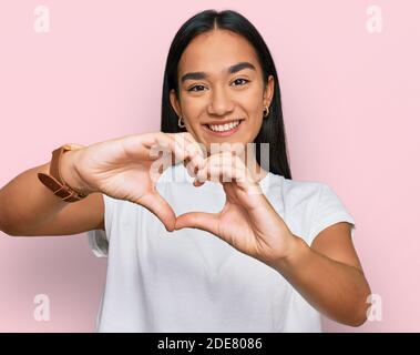 Young asian woman wearing casual white t shirt smiling in love doing heart symbol shape with hands. romantic concept. Stock Photo