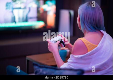Moscow - November 28 2020: Woman holding new Dualsense controller joystick of Sony PlayStation 5 gaming console at home. Playing games with her Stock Photo