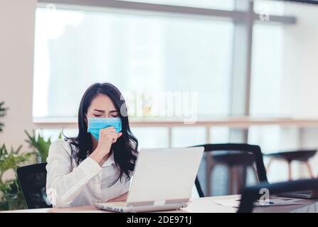 Stressed Young business woman wear face mask and  coughing in office Stock Photo