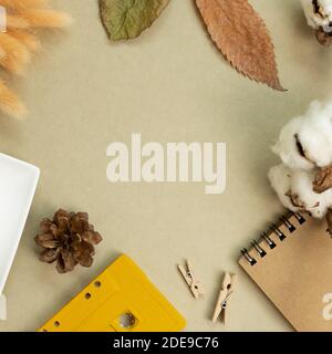 Winter and autumn concept. Notebook, audio cassette tape, cotton plant, dry leaves on khaki green background. flat lay, top view, copy space Stock Photo