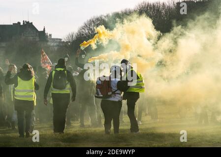 Protesters take shelter from the police on the Invalides esplanade, drowned in a cloud of yellow smoke from the smoke. Several thousand people gathered to demonstrate during act 14 of the protest movement against the rise in the cost of living, taxes and fuel, yellow jackets (Gilets Jaunes). The Parisian course took place between the Champs-Elysées and the Place des Invalides in relative calm. There were some clashes between demonstrators and the police, who used tear gas. Paris, France, February 16, 2019. Photo by Samuel Boivin / ABACAPRESS.COM Stock Photo