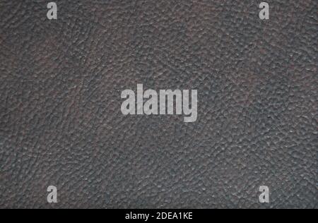 A fragment of black genuine leather with shades of dark brown and a hack-like pattern. Close-up. Stock Photo